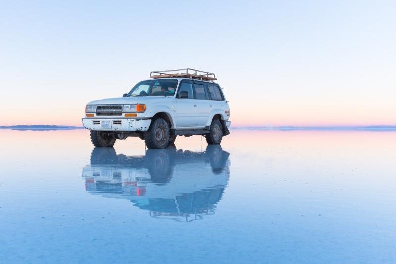 Four-wheel-drive vehicle reflected on the flooded Salar de Uyuni